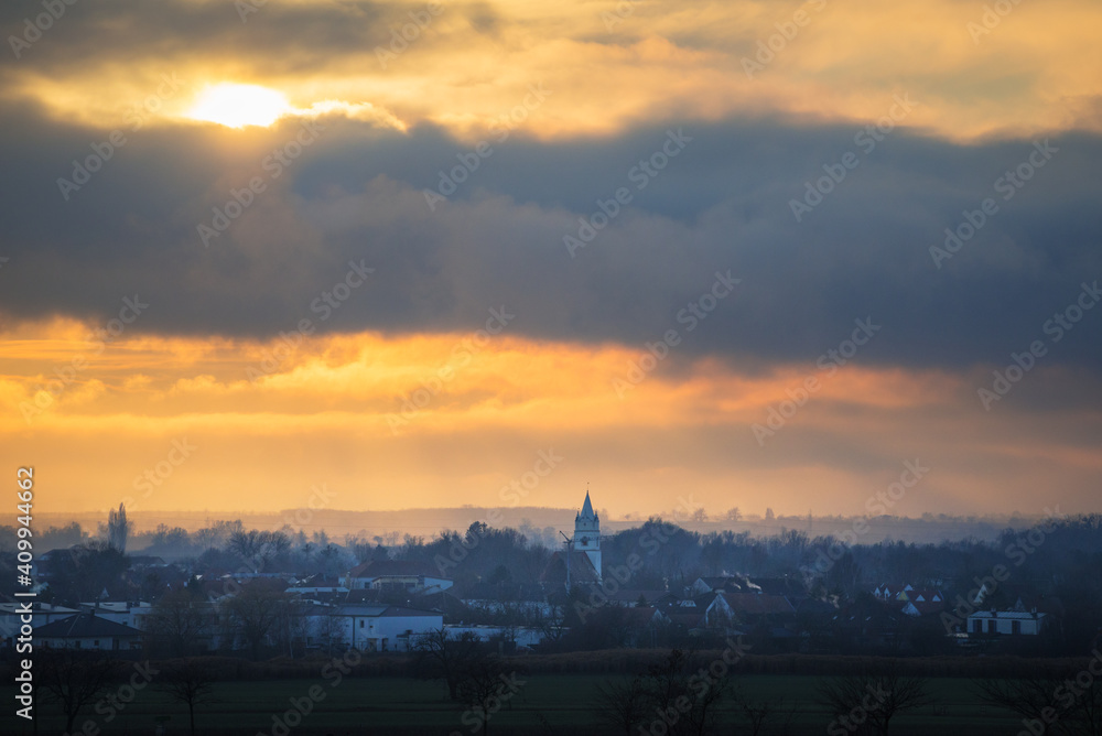 Village of Oslip at sunset with clouds and mist
