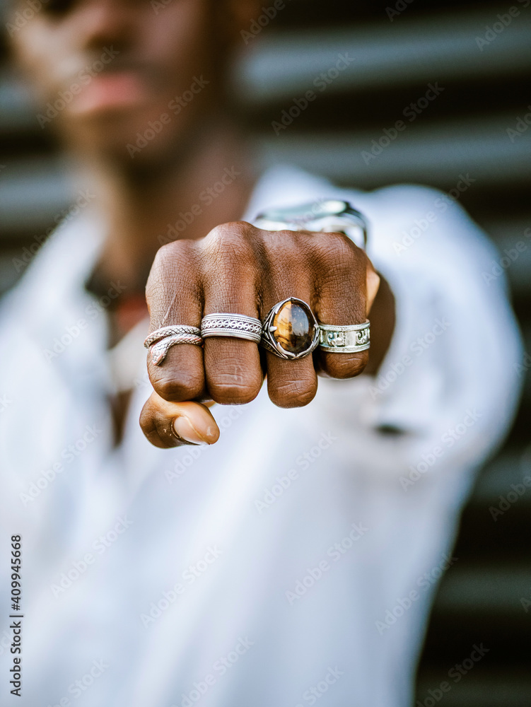 © Albert Morcillo/ADDICTIVE STOCK - Blurred anonymous African American stylish male showing fist with various trendy silver rings