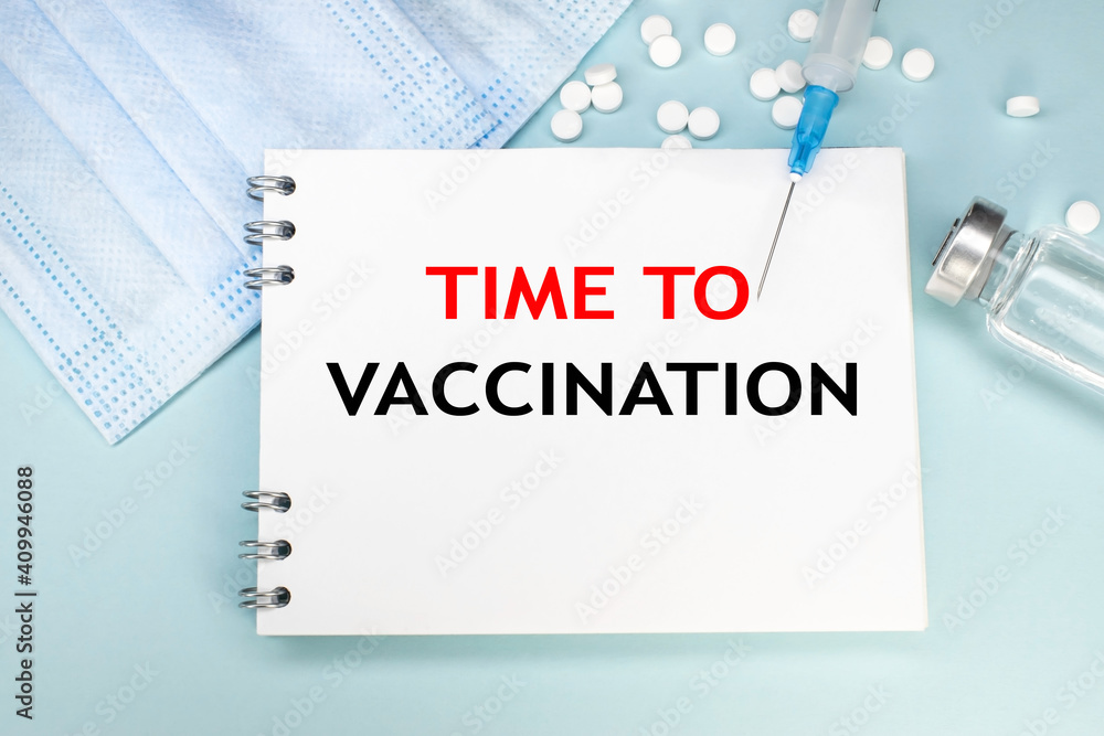 The time for vaccination is written on a notebook that lies on the medical mask near the ampoule and syringe. vaccination of the population. Medical concept The time for vaccination is written on a notebook that lies on the medical mask near the ampoule and syringe. vaccination of the population. Medical concept