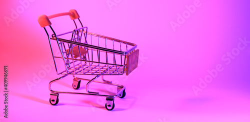 Shoping trolley with in trendy neon light. Gradient pink-blue glow. Concept art. Retro 80s. Minimalism shopping concept. Toy shopping trolley, neon