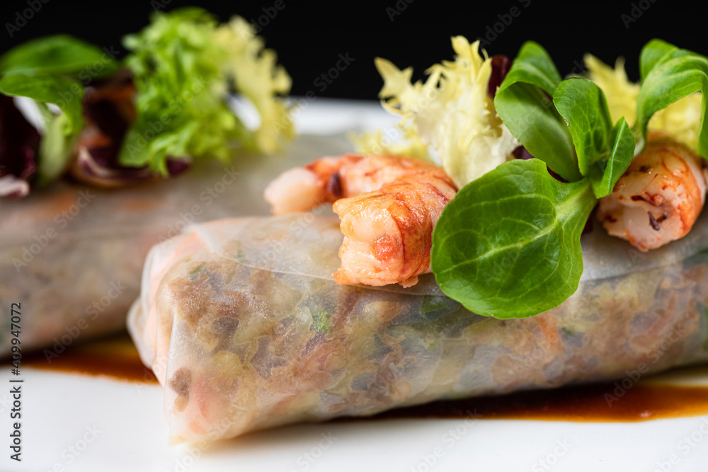 Closeup of delicious duck cannelloni garnished with shrimps and greenery and served on plate in Asian restaurant Closeup of delicious duck cannelloni garnished with shrimps and greenery and served on plate in Asian restaurant