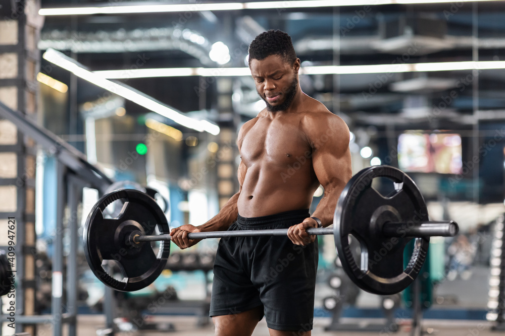 Muscular shirtless bodybuilder exercising with barbell at gym Muscular shirtless bodybuilder exercising with barbell at gym