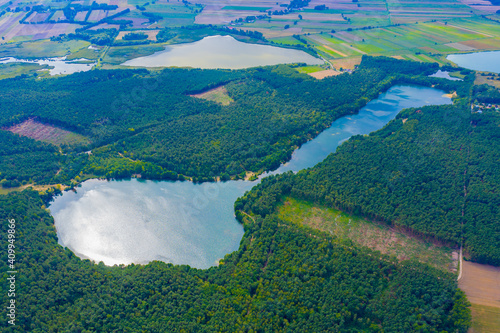 Aerial view of wild forest lake in summer. Small blue lake in green pine tree forest in rural