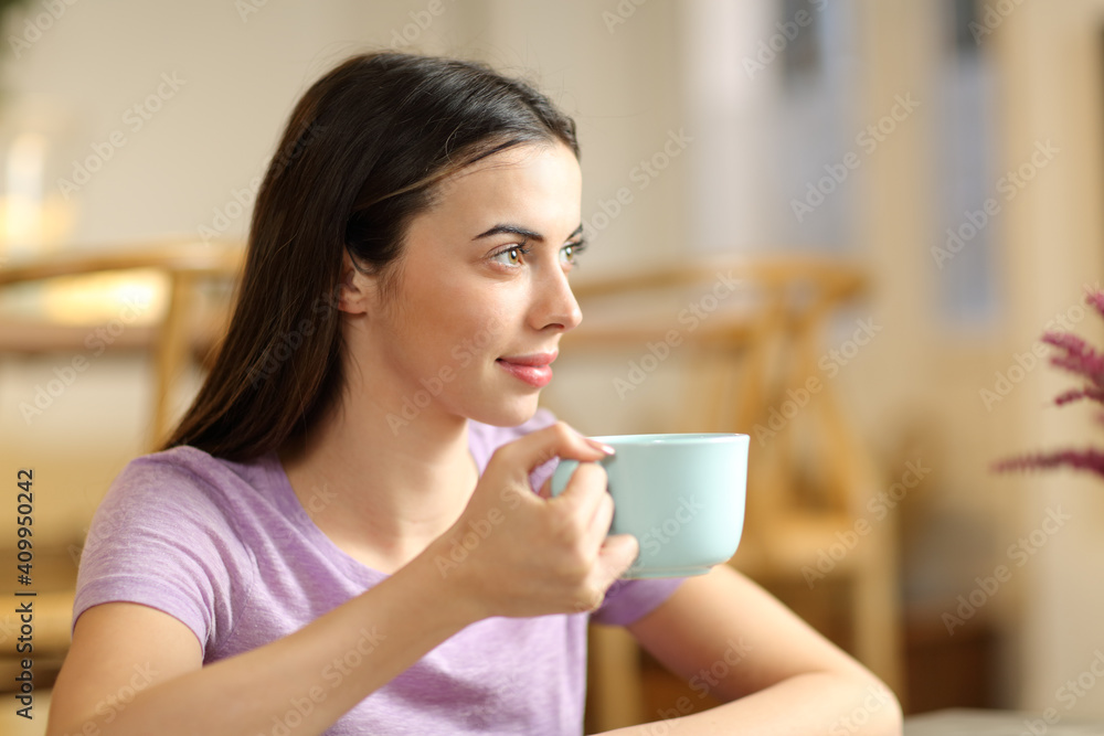 Woman looking away drinking coffee at home Woman looking away drinking coffee at home