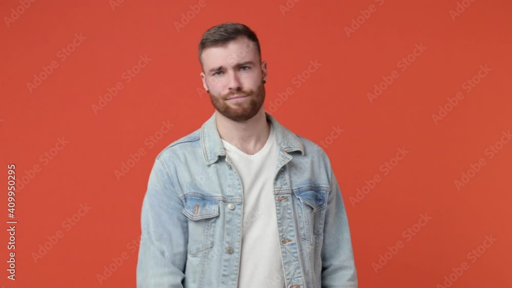 Confused bearded young man 20s in casual white t-shirt denim jacket isolated on orange background studio. People lifestyle concept. Point index finger himself ask say who me no thanks i do not need it Confused bearded young man 20s in casual white t-shirt denim jacket isolated on orange background studio. People lifestyle concept. Point index finger himself ask say who me no thanks i do not need it