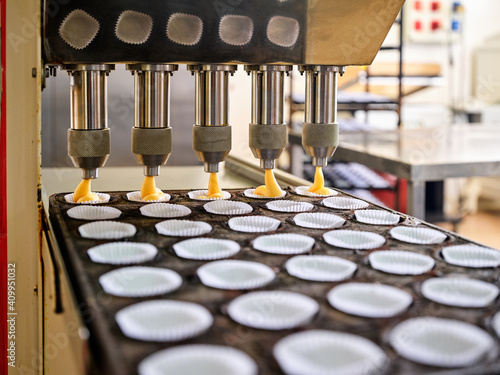 Automatic industrial dough filling machine used during process of muffins production in professional bakery