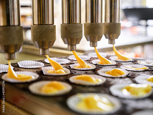 Automatic industrial dough filling machine used during process of muffins production in professional bakery