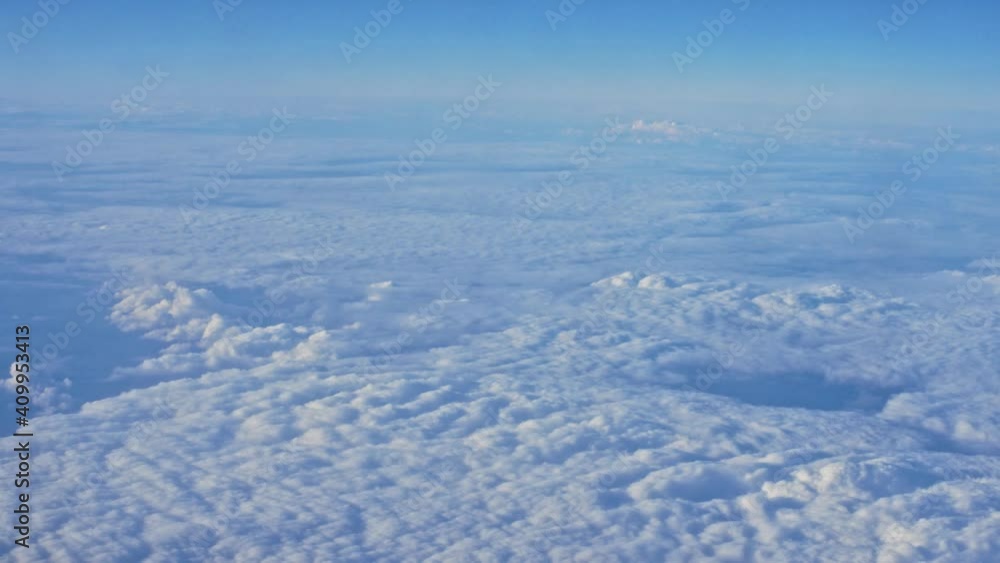 View from plane window to white clouds in the blue sky View from plane window to white clouds in the blue sky