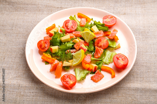 Salmon salad with cherry tomatoes and green salad in a plate of gray tablecloth.