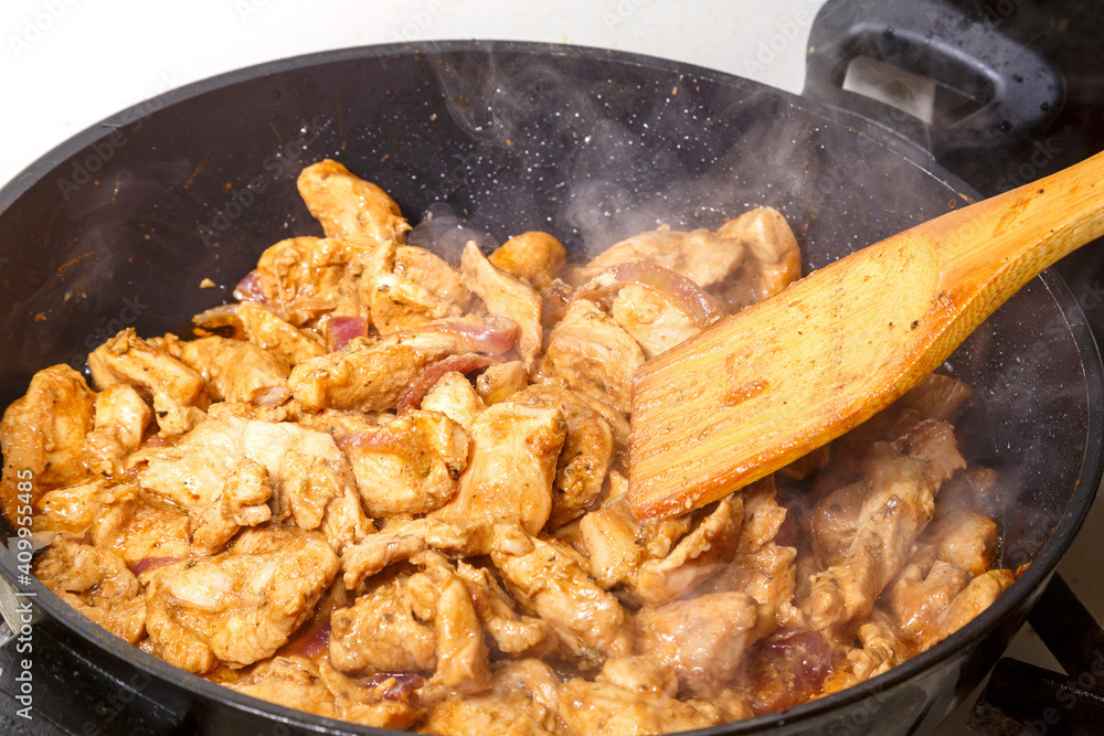 Chicken fillet in soy sauce with lemon juice stirring a wooden spatula in a frying pan. Chicken fillet in soy sauce with lemon juice stirring a wooden spatula in a frying pan.