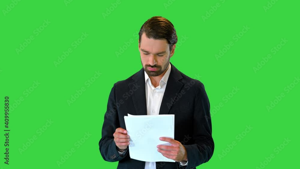 Serious Young Businessman reading documents while walking on a Green Screen, Chroma Key. Serious Young Businessman reading documents while walking on a Green Screen, Chroma Key.