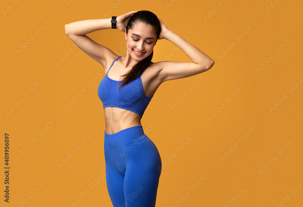 Obraz premium Smiling Sporty Woman Posing Isolated On Orange Background