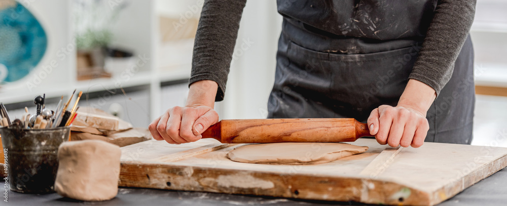 Woman using rolling pin on clay