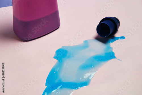 Top view of liquid detergent spilled from plastic cap on pink background in studio