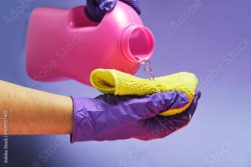 Crop anonymous person with plastic bottle pouring liquid detergent in a rag in studio