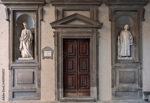 Florence, Italy - 2020, January 18: Old wooden entry door to the Uffizi Gallery Museum. Cosimo and Lorenzo Medici marble statues on either side.. photo