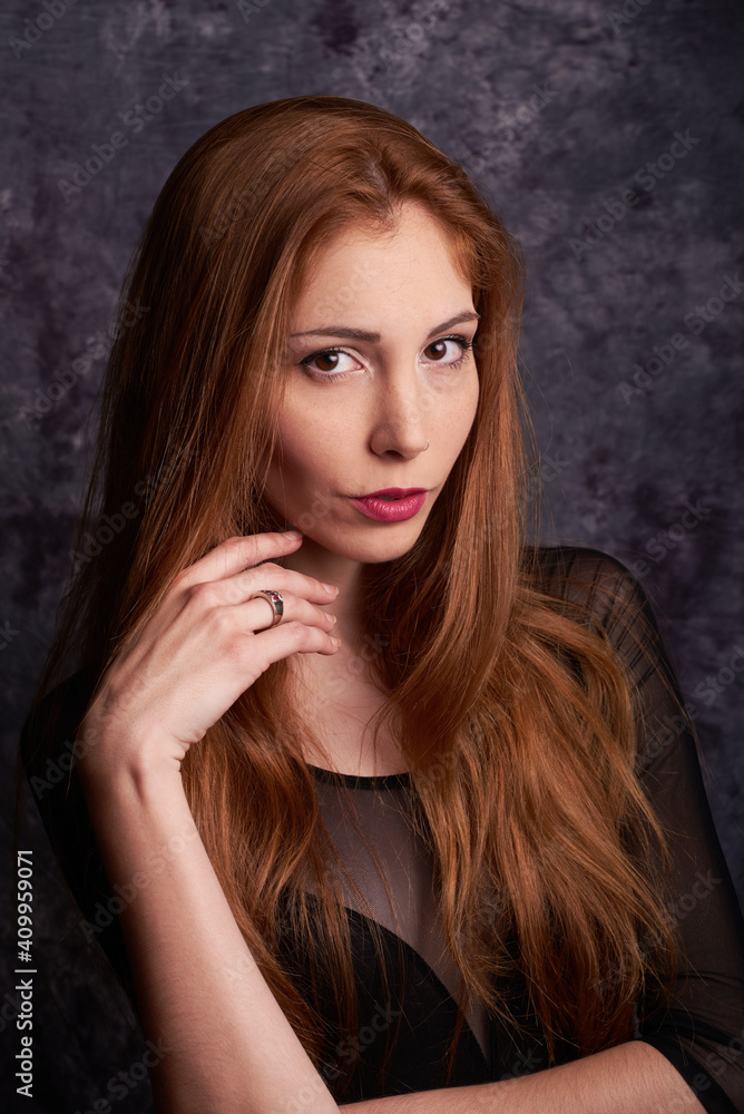 Calm female model in stylish clothes standing in studio with red hair and looking at camera Calm female model in stylish clothes standing in studio with red hair and looking at camera