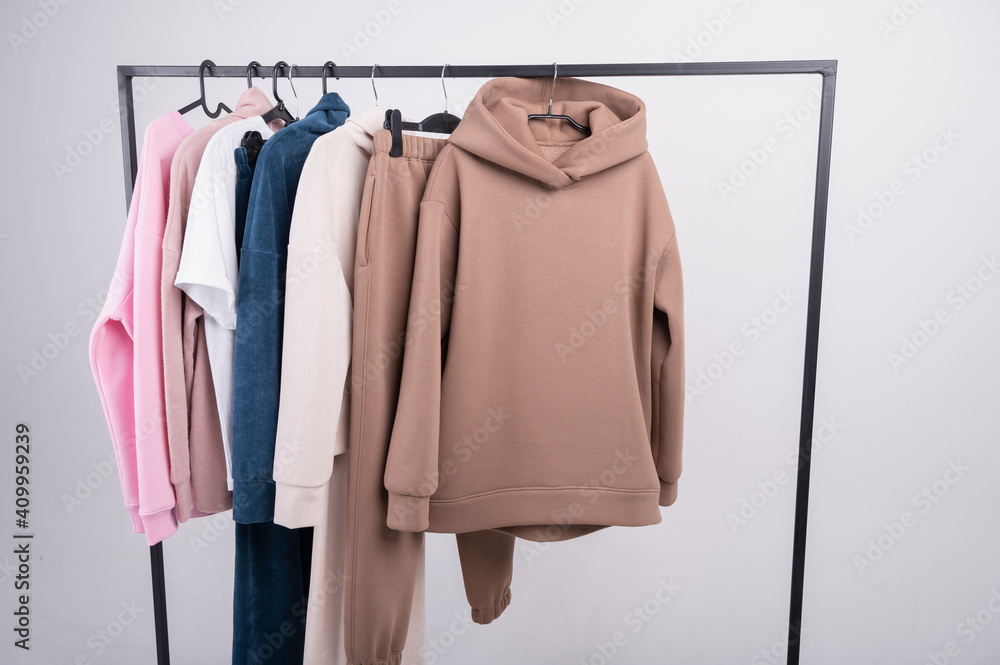 Fashionorange hoodie sweatshirt closeup with sweater and brown shirt on hanger background Fashionorange hoodie sweatshirt closeup with sweater and brown shirt on hanger background