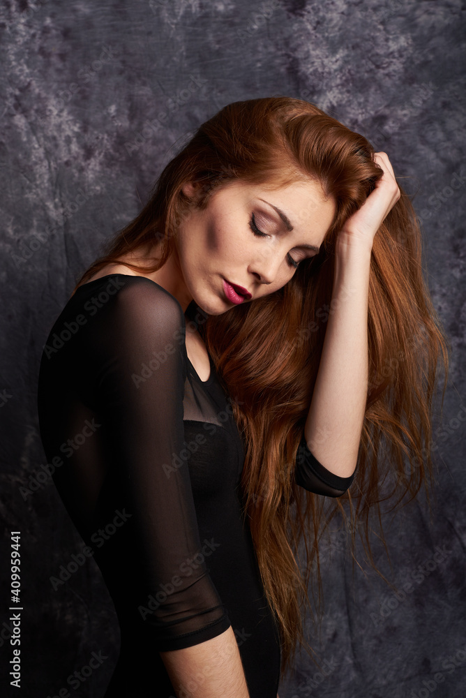 Side view of calm female model in stylish clothes standing with eyes closed in studio with red hair Side view of calm female model in stylish clothes standing with eyes closed in studio with red hair