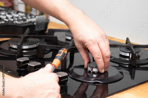 Gas stove repair. Service warranty repair of household appliances. A man repairs a gas stove at home. Burner repair