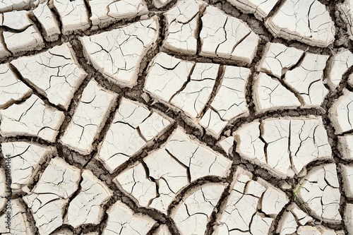 Top view closeup textured background of rough cracked barren waterless soil during drought photo