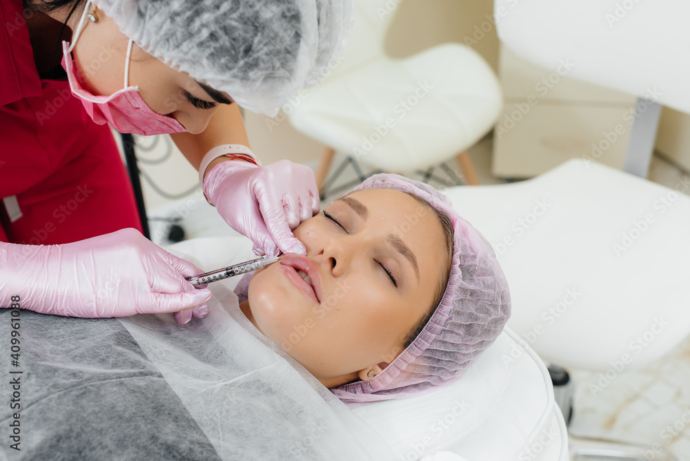 Obraz premium Cosmetology procedure for lip augmentation and wrinkle removal for a young beautiful girl. Cosmetology