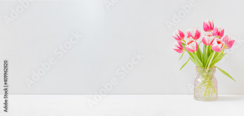 Home interior with decor elements. Pink tulips in a vase on a light background #409962820