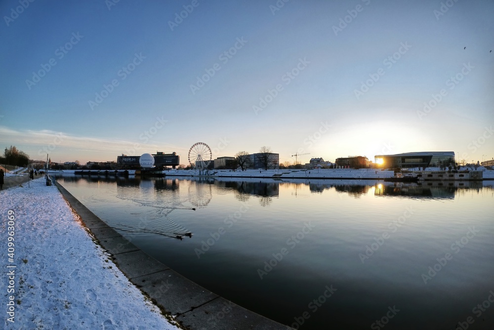 Krakow, South Poland - January 31, 2021: Pan shot of Vistula river against polish building located at the center of the city during peaceful sunset sunrise in winter. Krakow cityscape