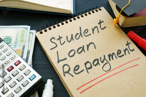 Student loan repayment sign, notepads, calculator and cash. photo