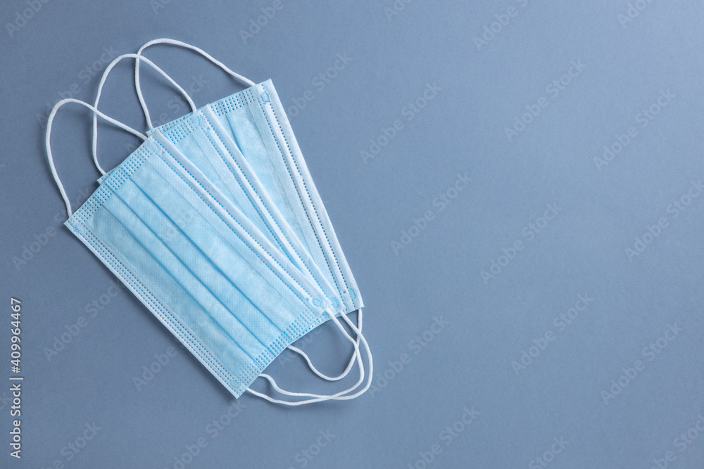 Medical protective, blue face masks, on grey background, close-up, flatly, minimal style, copy space. Hygiene concept, protective equipment, prevention of spread of viral infections, new normal Medical protective, blue face masks, on grey background, close-up, flatly, minimal style, copy space. Hygiene concept, protective equipment, prevention of spread of viral infections, new normal