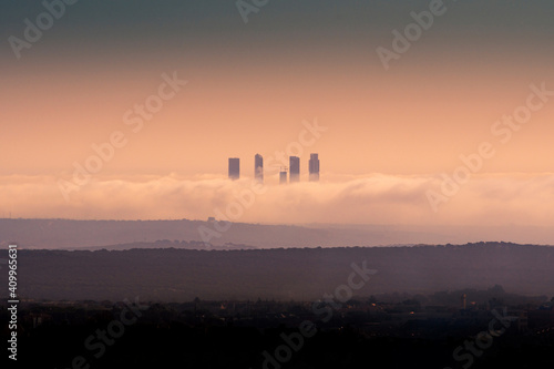 Amazing view of skylines of Cuatro Torres Business Area surrounded by thick clouds at sunset in Madrid photo