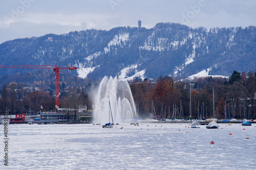 Fountain at lake Zurich, Switzerland, with snow mountain Uetliberg in the background.