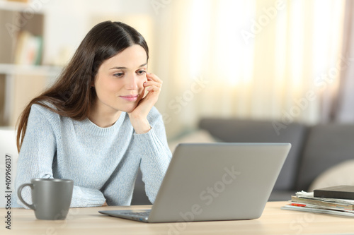 Pensive woman using laptop at home