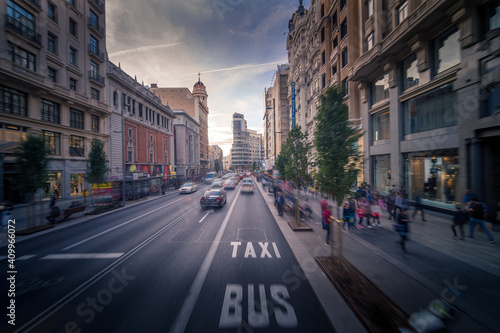 Long exposure of active traffic on road and sidewalk in Madrid in evening