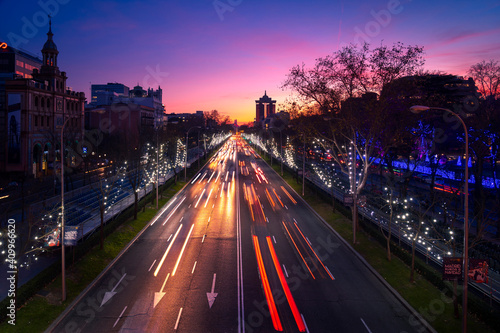 Amazing view of red and white traffic light trails on road in Madrid under sunset sky