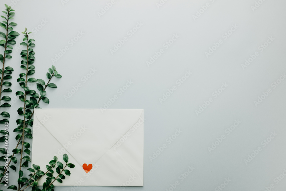 Minimal composition with a white envelope, heart and green leaves Minimal composition with a white envelope, heart and green leaves