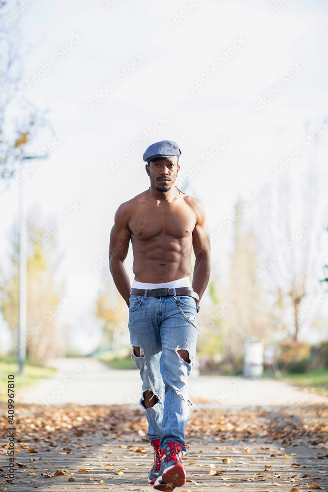 Determined African American male with naked muscular torso walking with