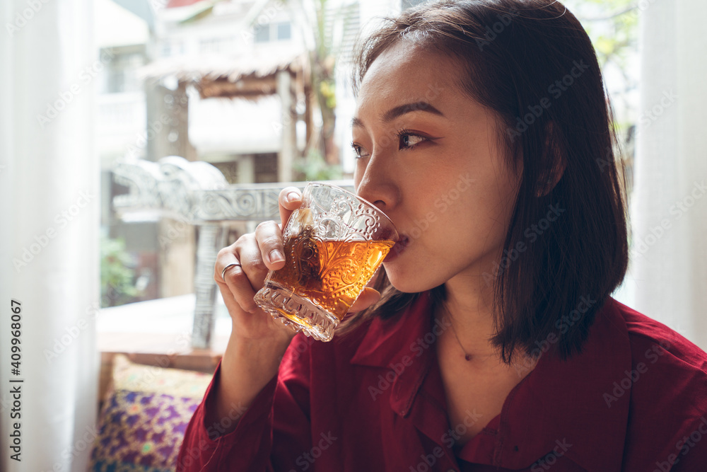 Young Asian female tourist sitting at table set for breakfast and enjoying hot tea while resting in cozy room with traditional oriental items in hotel in Taiwan Young Asian female tourist sitting at table set for breakfast and enjoying hot tea while resting in cozy room with traditional oriental items in hotel in Taiwan