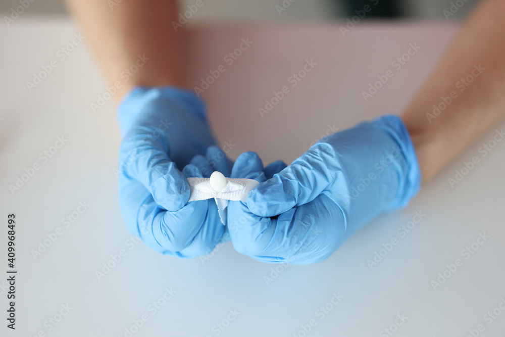 Doctors hands in rubber gloves opening rectal suppository closeup Doctors hands in rubber gloves opening rectal suppository closeup