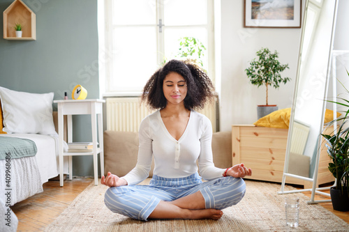Portrait of young woman indoors at home, doing yoga exercise.