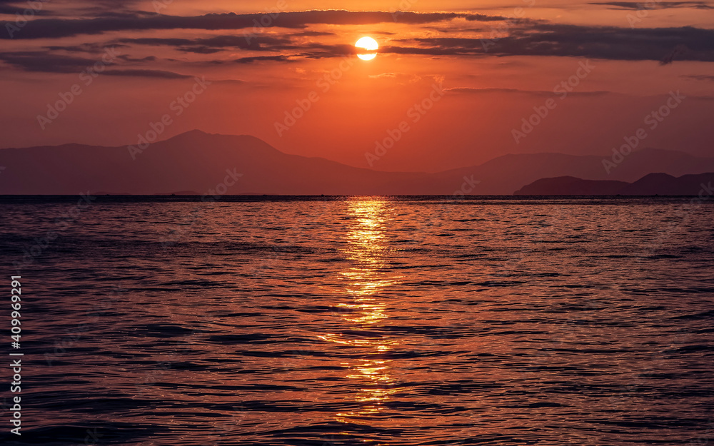 orange fiery sundown sky with some clouds over calm sea, nature background.