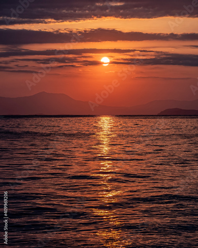 orange fiery sunrise sky with some clouds over calm sea  nature background.