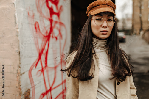 Принти на полотні Long-haired woman in corduroy and beige coat looks into camera outside