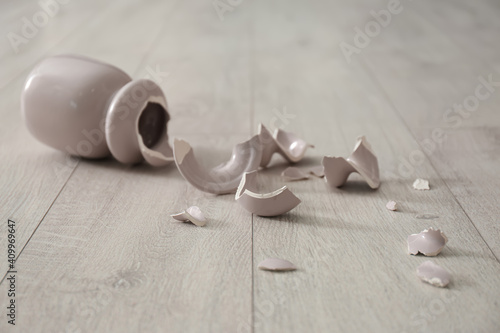 Broken pink ceramic vase on wooden floor photo