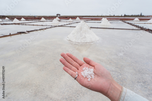 Crop anonymous female traveler demonstrating white salt crystals in hand while visiting Jingzaijiao Tile paved Salt Fields in Tainan city in Taiwan photo