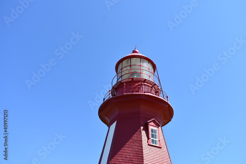 top of red and white lighthouse in the blue sky