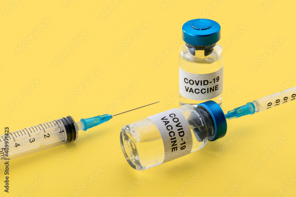 Coronavirus COVID-19 vaccine. Vials with syringes isolated on yellow background, concept composition with copy space Coronavirus COVID-19 vaccine. Vials with syringes isolated on yellow background, concept composition with copy space