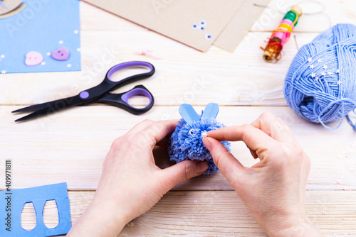 How to make a bunny from pom-poms for Easter decor. Children's art project. DIY concept. Hands make a blue Easter bunny out of a pompom. Step by step photo instruction photo