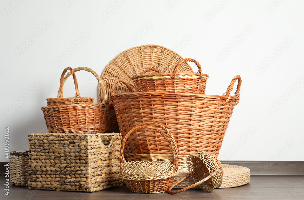 Many different wicker baskets made of natural material on floor near light wall Many different wicker baskets made of natural material on floor near light wall