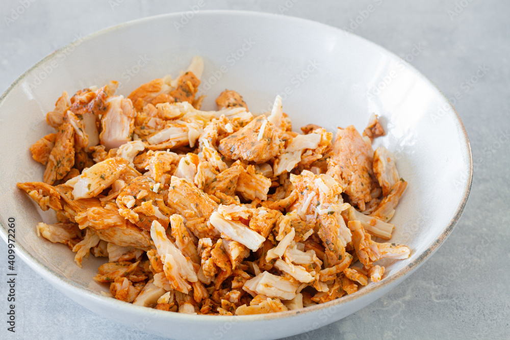 High angle of white bowl with shredded grilled chicken meat for Caesar salad on gray table High angle of white bowl with shredded grilled chicken meat for Caesar salad on gray table